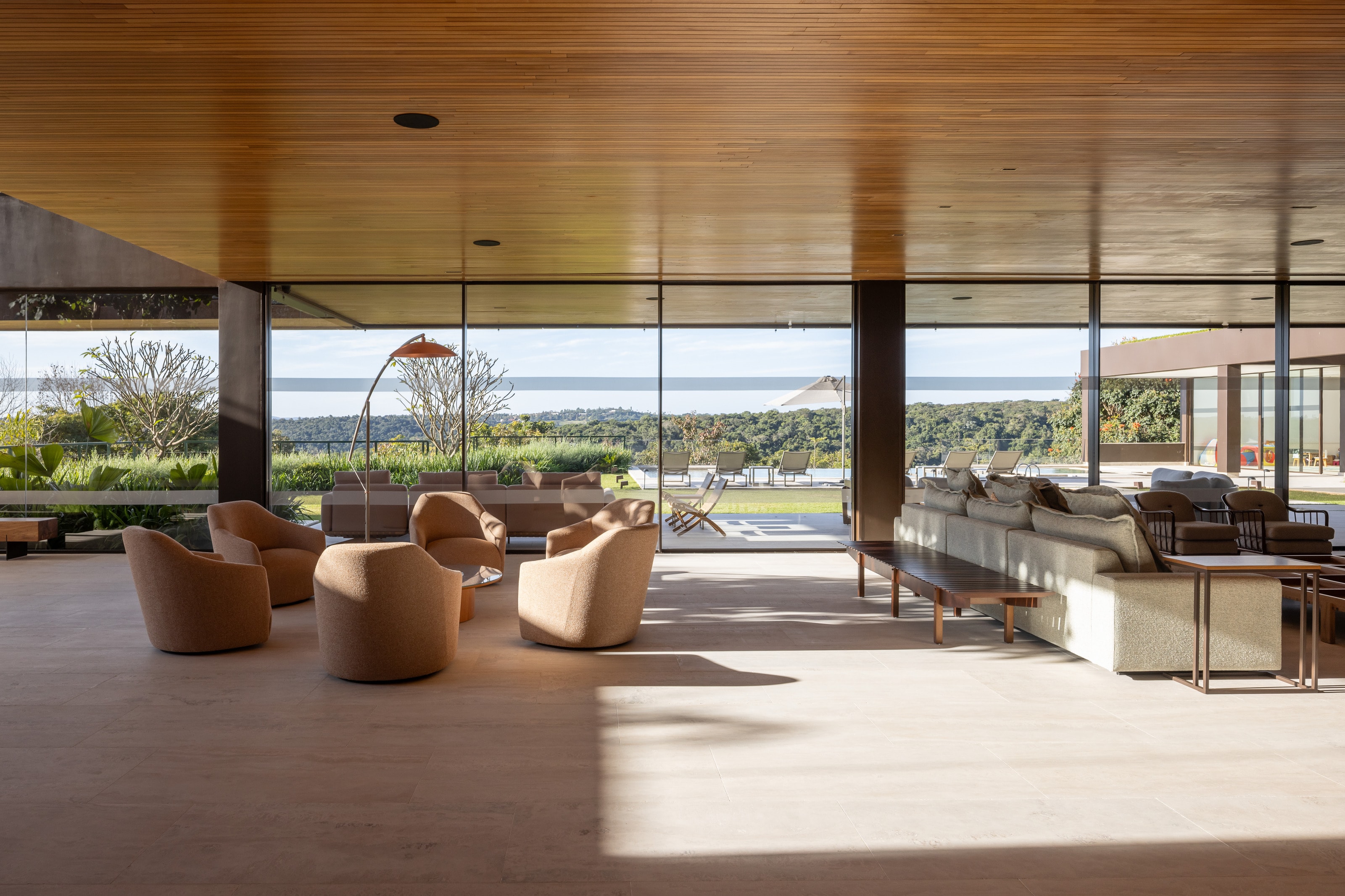 Sunset House: sala de estar com poltronas ao redor de mesa de centro, forro de madeira ripado e vista aberta para o horizonte, obra executada pela Zacharias Engenharia